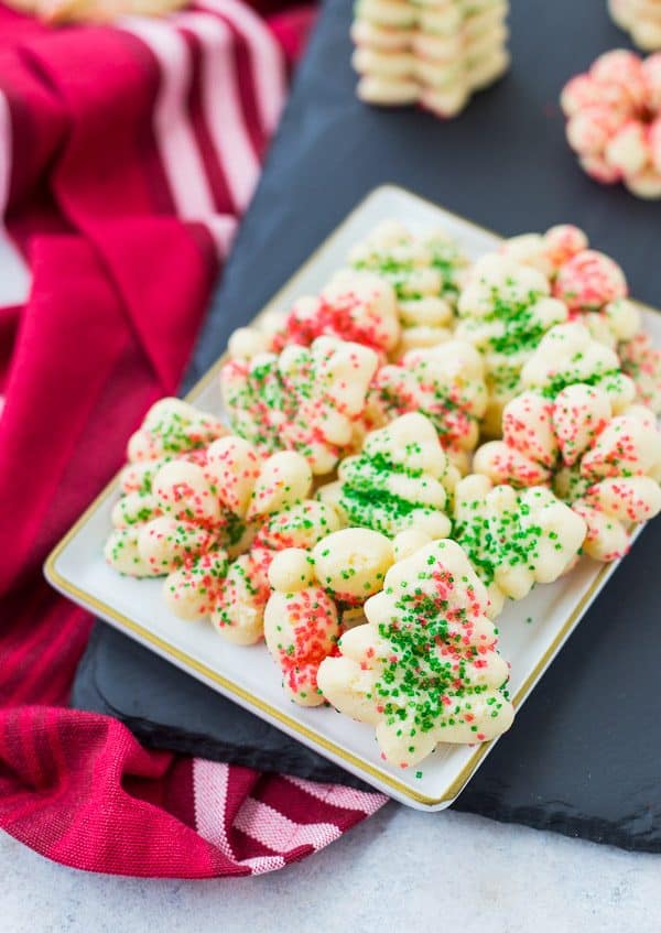 Small plate with several spritz cookies decorated with red and green sugar.