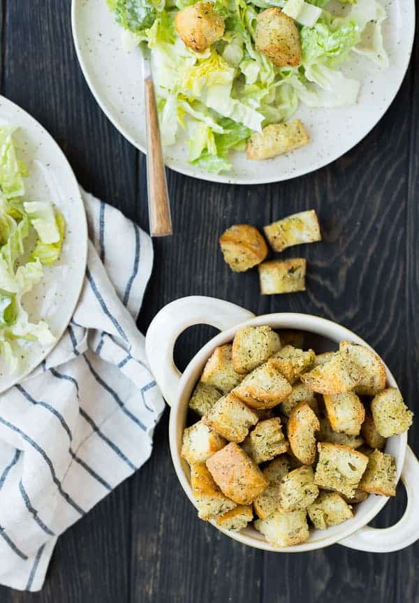 Overhead of caesar croutons on black wooden background.