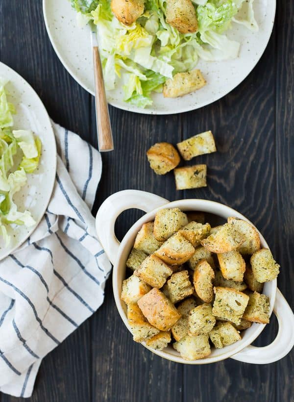 Overhead of croutons in bowl and caesar salads.