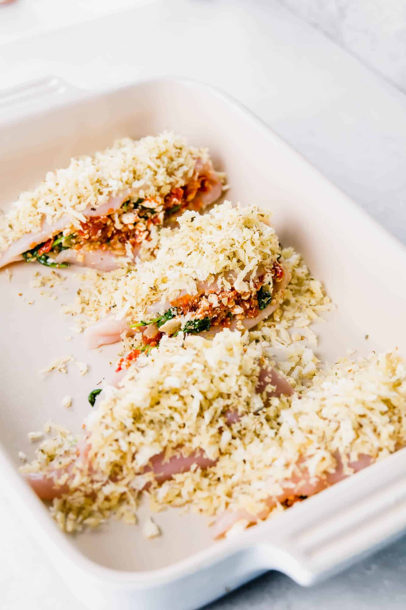 Stuffed and breaded chicken breasts in baking dish, before baking.