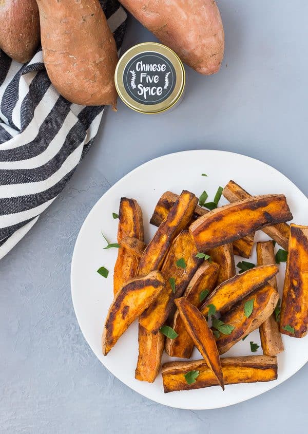 Overhead of sweet potato wedges on round white plate, garnished with chopped parsley.