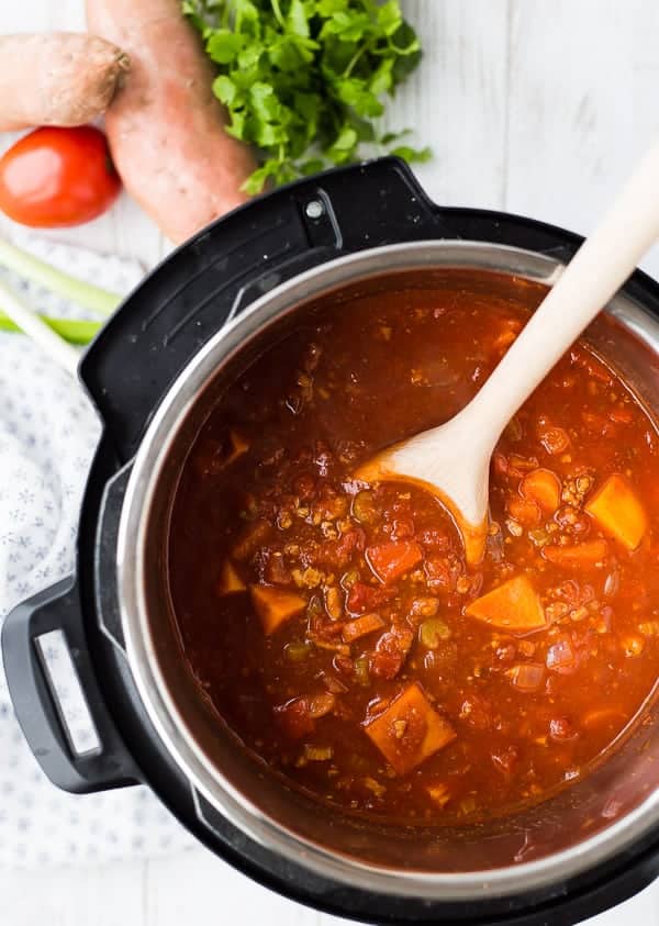 Overhead of chili in Instant Pot, with wooden spoon.