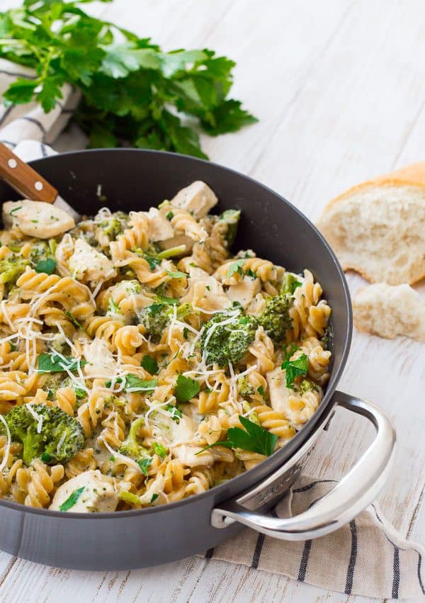 Partial of chicken alfredo garnished with shredded Parmesan and chopped parsley in pan.