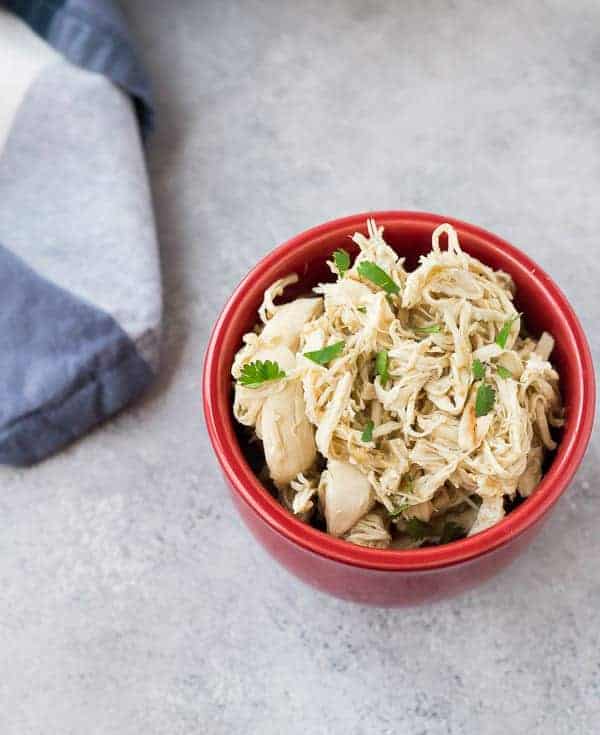 Overhead of small red bowl containing shredded chicken.