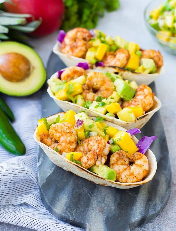 These Shrimp Tacos are a refreshing taste of the tropics thanks the zesty avocado, mango and pineapple salsa. They're easy to make and are a hit for any party or taco night. The extra salsa is amazing on chips or sprinkled on a salad! Get the quick and easy taco recipe on RachelCooks.com!