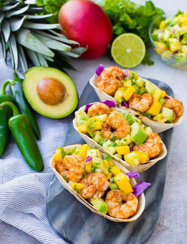 These Shrimp Tacos are a refreshing taste of the tropics thanks the zesty avocado, mango and pineapple salsa. They're easy to make and are a hit for any party or taco night. The extra salsa is amazing on chips or sprinkled on a salad! Get the quick and easy taco recipe on RachelCooks.com!