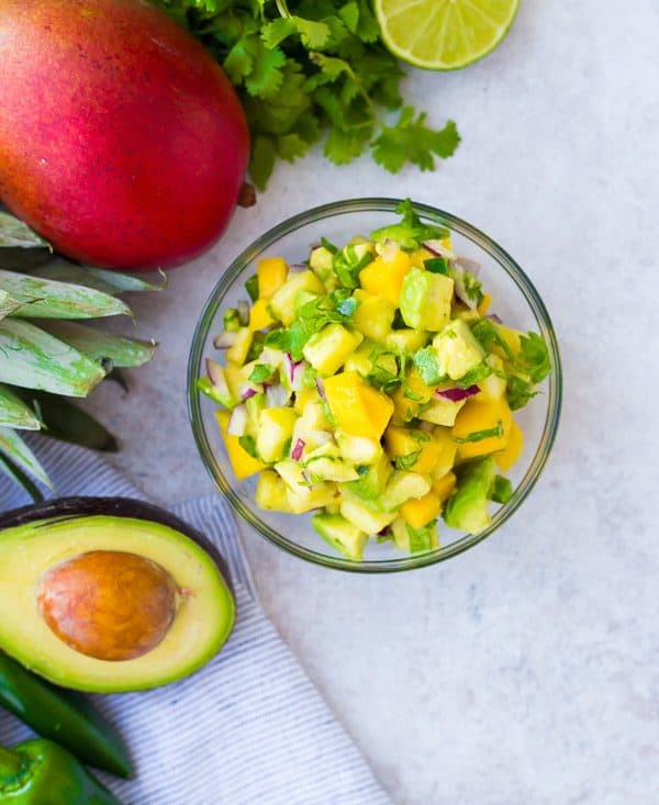 Mango Avocado Salsa is the perfect topping to any taco or salad, and it's irresistible piled up on a chip! You'll love the creamy avocado, sweet mango, and tart pineapple in every bite! Get the easy salsa recipe on RachelCooks.com!