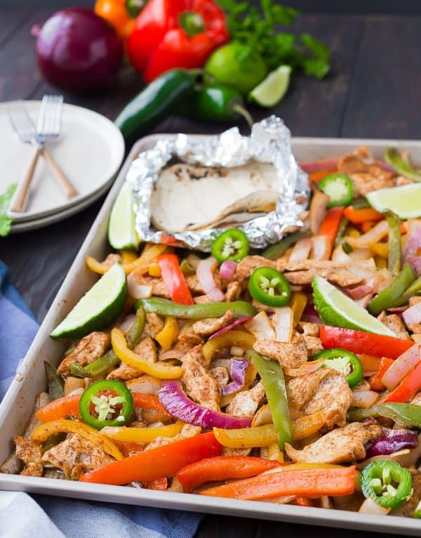 Partial image of fajita makings on sheet pan, with uncooked veggies in background.