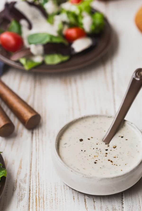 Salad dressing in a small bowl with a brown spoon.