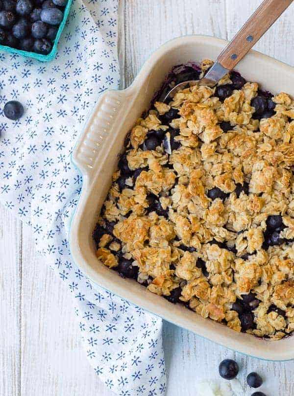 Partial image of blueberry crisp in baking dish with spoon inserted.