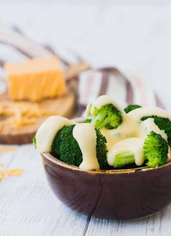 Closeup of round brown bowl containing broccoli and cheese sauce.