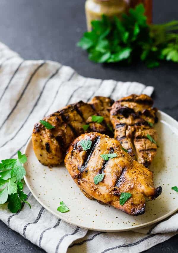 Overhead of three portions of grilled chicken on plate.