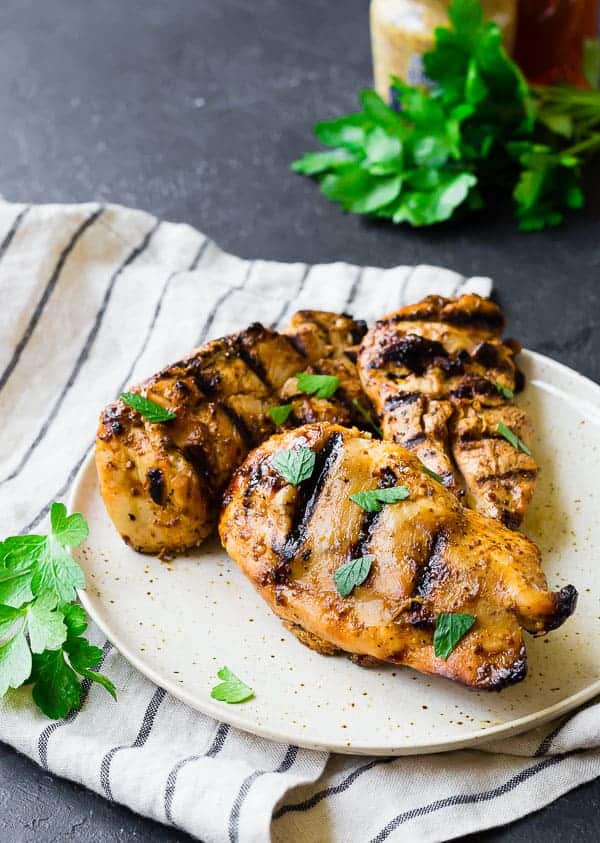 Three portions of chicken on round white plate, garnished with parsley.