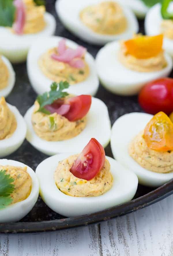 Closeup front view of deviled eggs with a variety of garnishes.