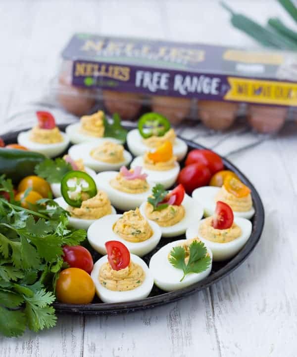 Front view of eggs on black tray with package of Nellie's eggs in background.