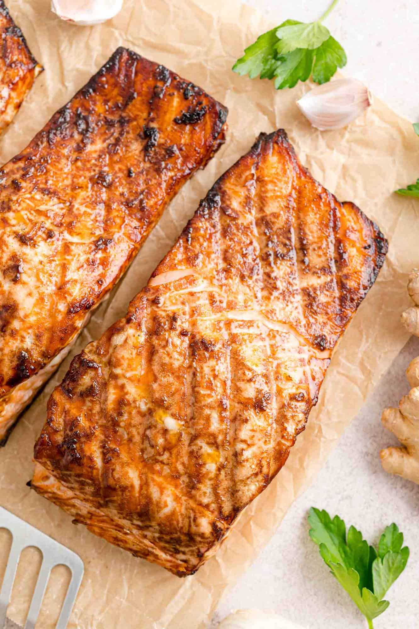 Overhead view of two grilled salmon fillets on parchment paper.