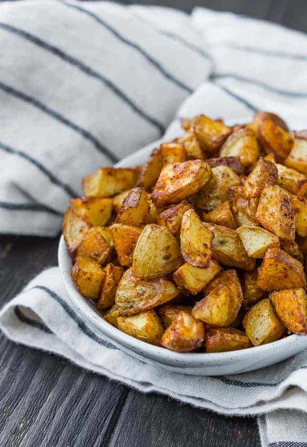 Small white bowl filled to the brim with small golden brown cuts of potato.