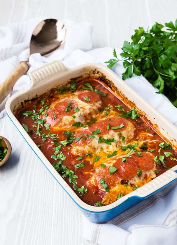 Three chicken breasts in blue rectangular baking dish.