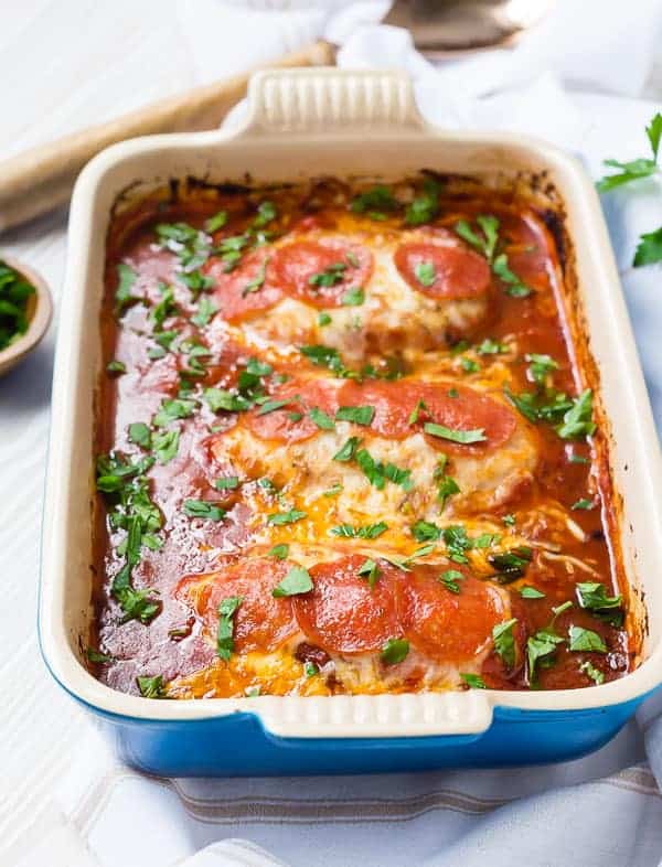 Front view of baked chicken in blue baking dish.