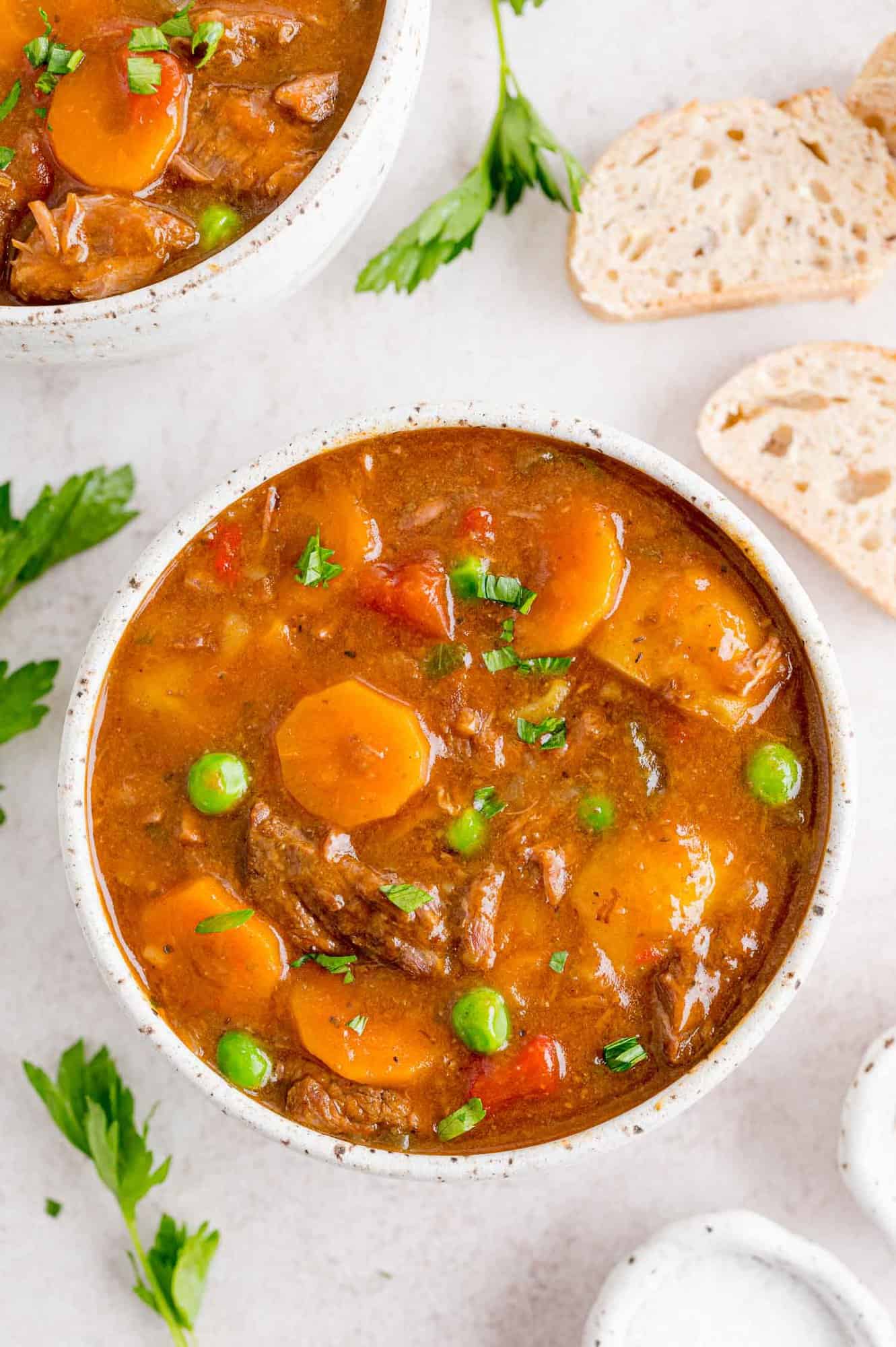 Overhead view of bowl of Instant Pot beef stew next to slices of bread.