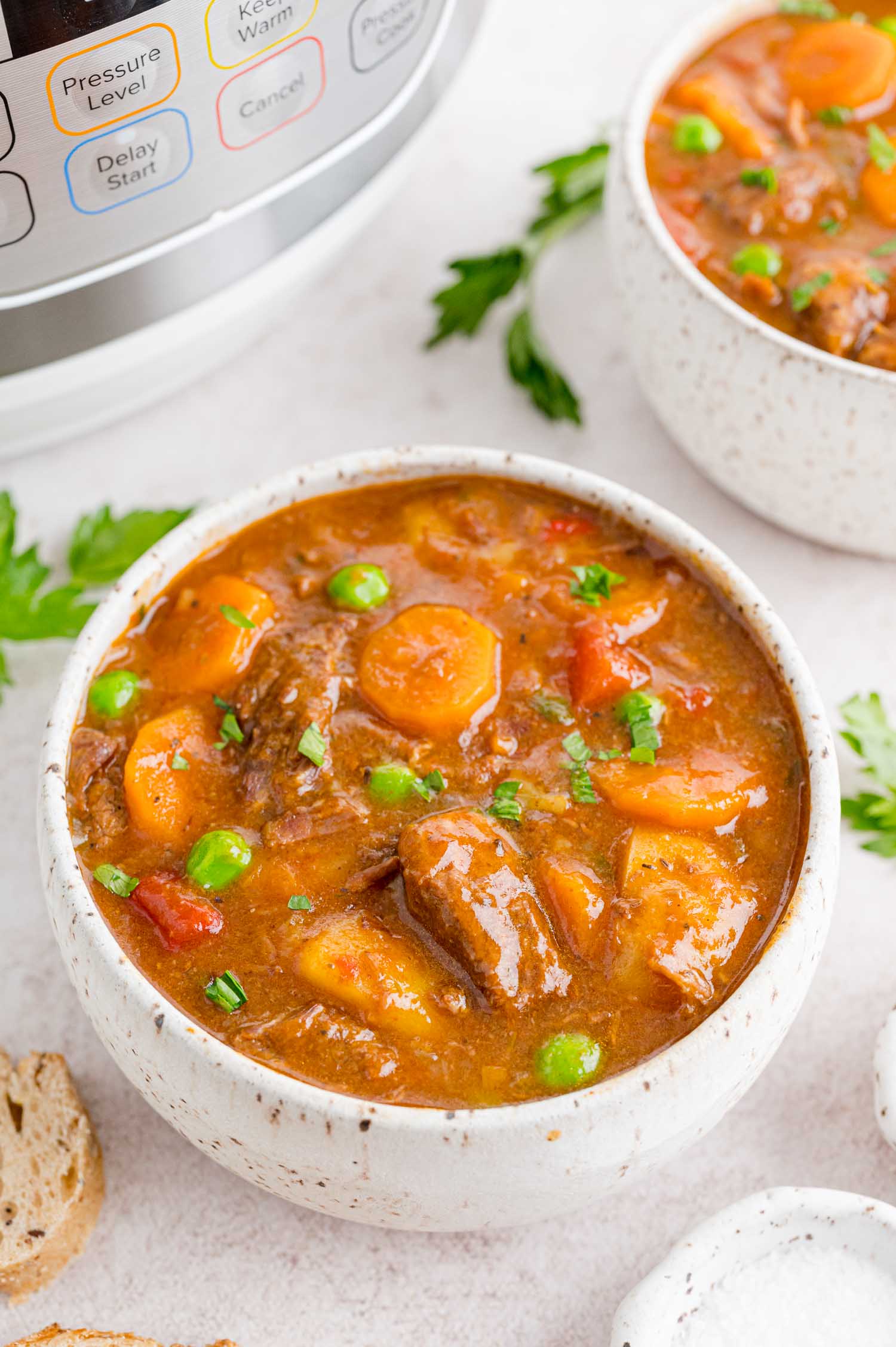 Two bowls of beef stew on a countertop next to the Instant Pot.