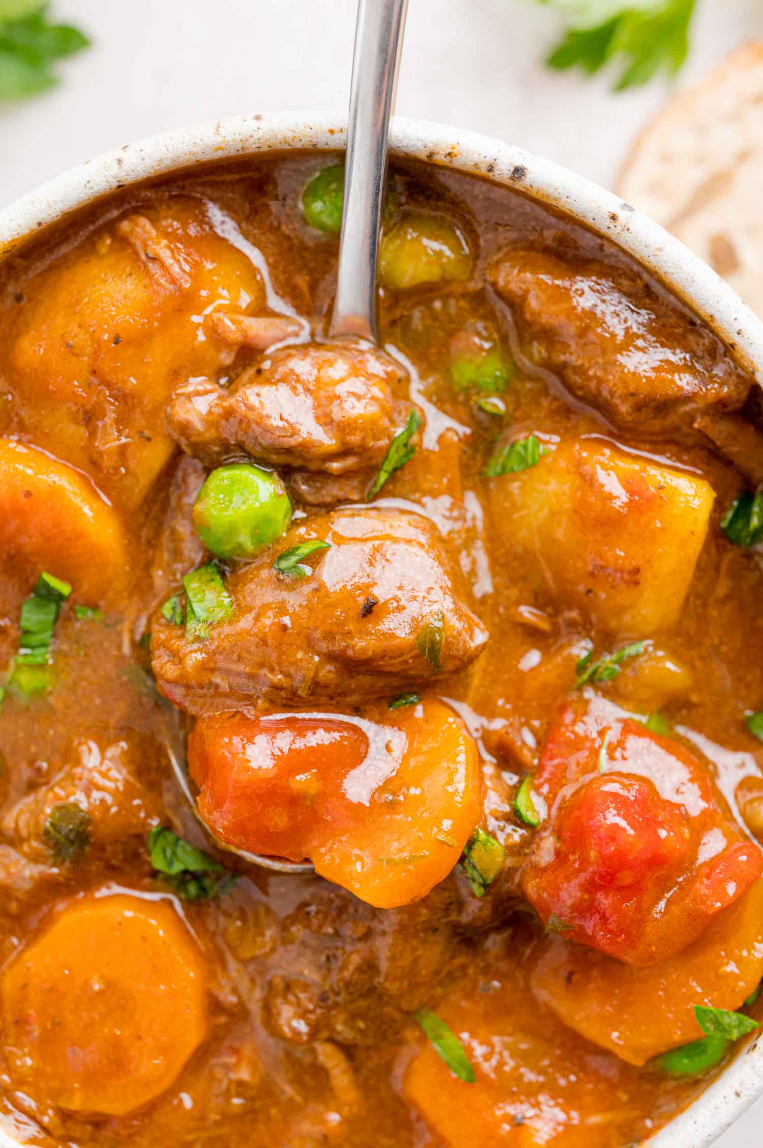 Close up overhead view of a spoonful of Instant Pot beef stew lifted from a bowlful.