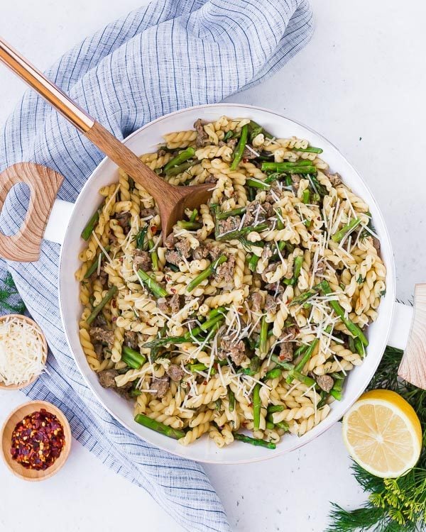 Overhead of prepared pasta in white pan with wooden handles.
