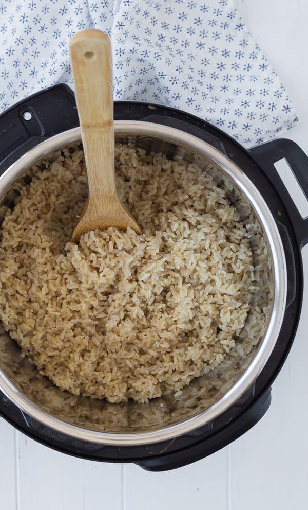 Overhead of cooked rice in Instant pot with wooden spoon inserted.