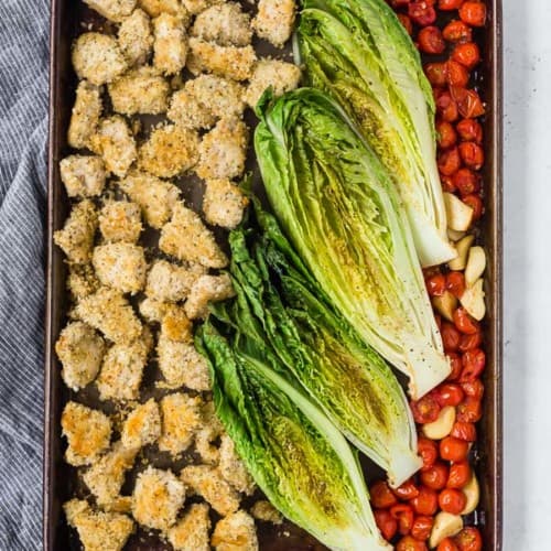 image of sheet pan dinner with crispy chicken, roasted romaine lettuce, and roasted tomatoes and garlic.