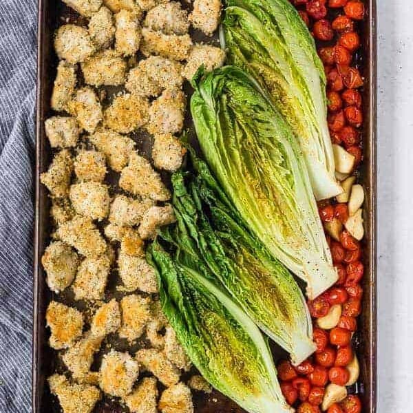 image of sheet pan dinner with crispy chicken, roasted romaine lettuce, and roasted tomatoes and garlic.