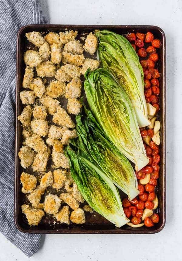 image of sheet pan dinner with crispy chicken, roasted romaine lettuce, and roasted tomatoes and garlic. 