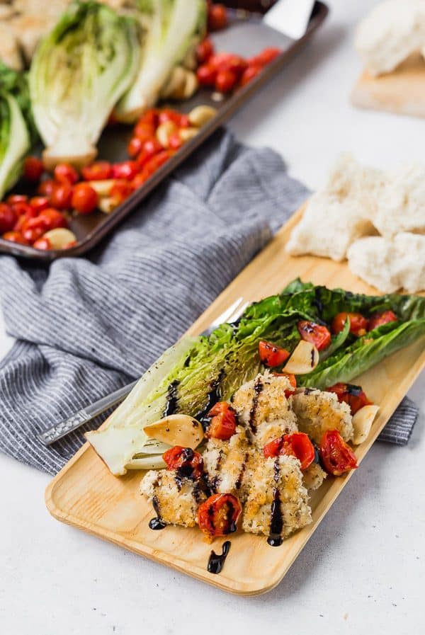 One serving of sheet pan dinner on rectangular wooden plate,