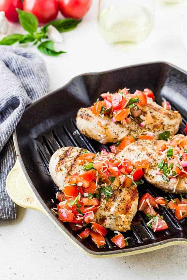 image of chicken in a grill pan topped with tomato and basil