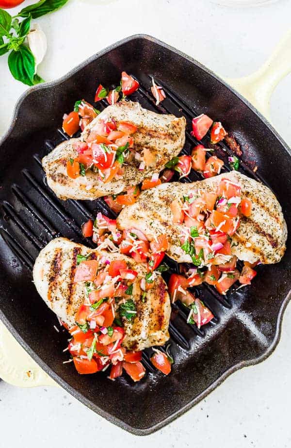 Overhead of three portions of bruschetta chicken in grill pan.