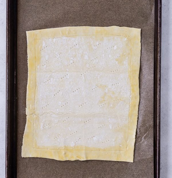 Image of unbaked puff pastry, demonstrating how to score it and poke it with a fork to form a crust for a tart. 