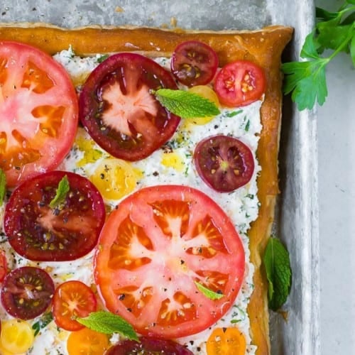 Image of herbed ricotta and fresh tomato tart, taken from above. Garnished with mint leaves.