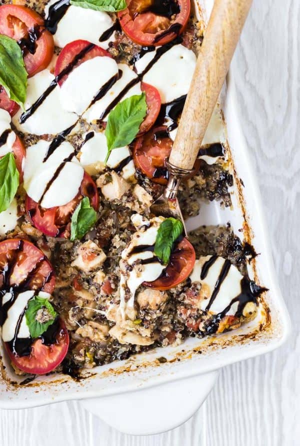 Partial overhead of quinoa bake with wooden handle spoon scooping a portion out.