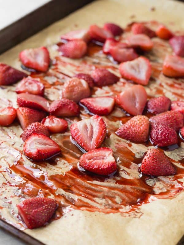 Image of roasted strawberries on a pan with parchment paper.