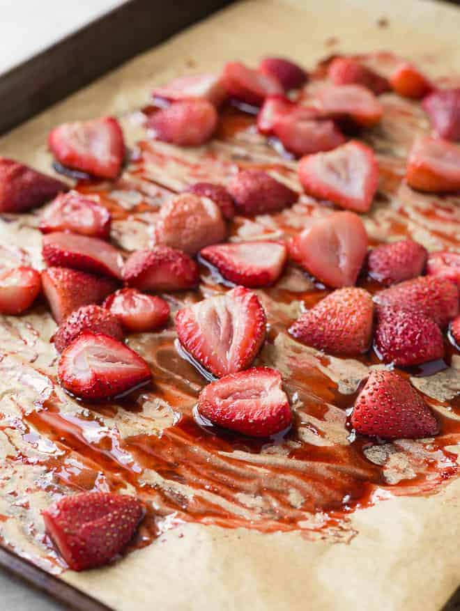 Image of roasted strawberries on a pan with parchment paper.