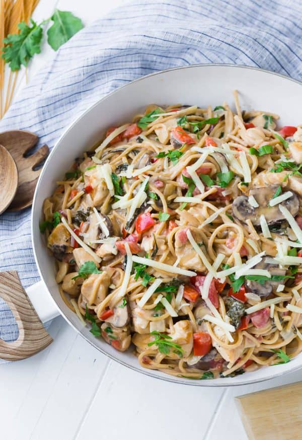 Image of one pan creamy chicken spaghetti garnished with parsley and extra cheese. 