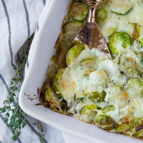 Cheesy brussels sprouts gratin with a spoon scooping out one big cheesy scoop.