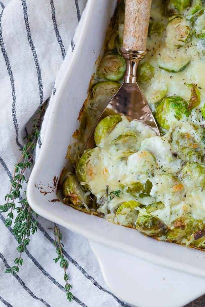 Cheesy brussels sprouts gratin with a spoon scooping out one big cheesy scoop.