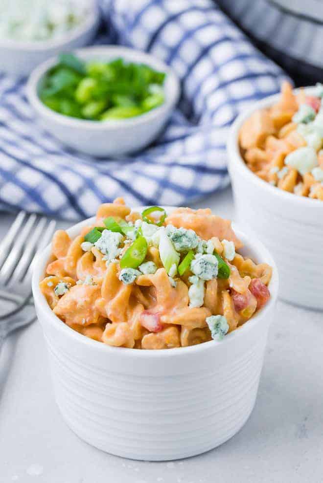 Image of a bowl of instant pot buffalo chicken pasta garnished with green onions and blue cheese.