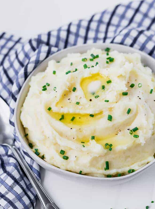 Creamy mashed potatoes in a bowl topped with melting butter and chives. 