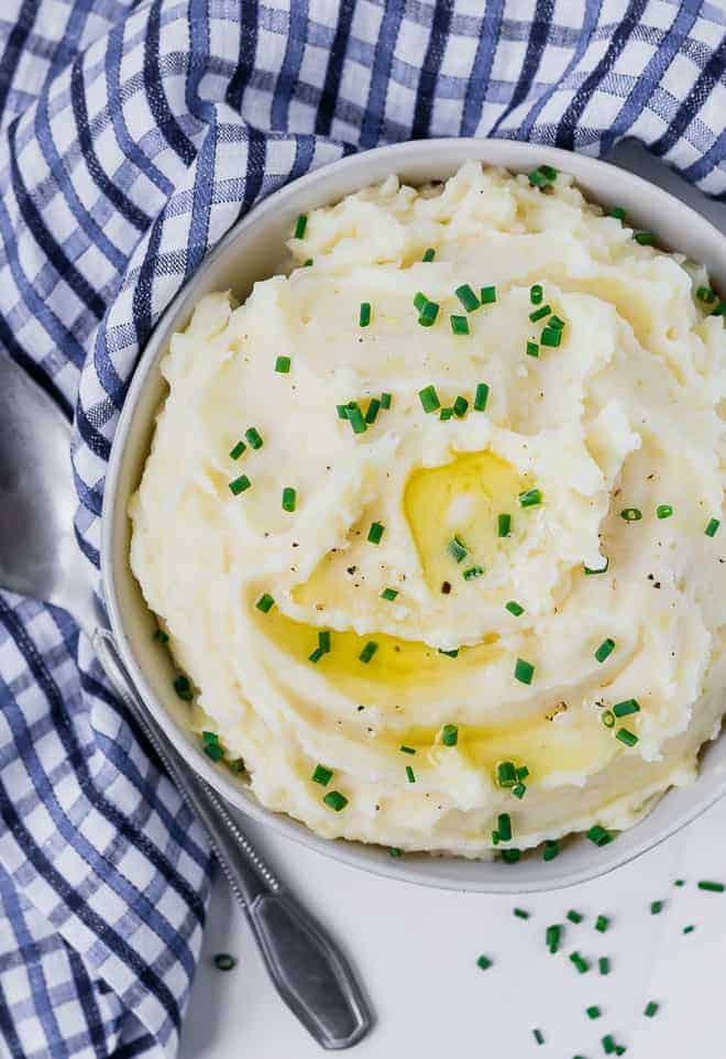 Beautiful mashed potatoes in a bowl, garnished with chives and butter.