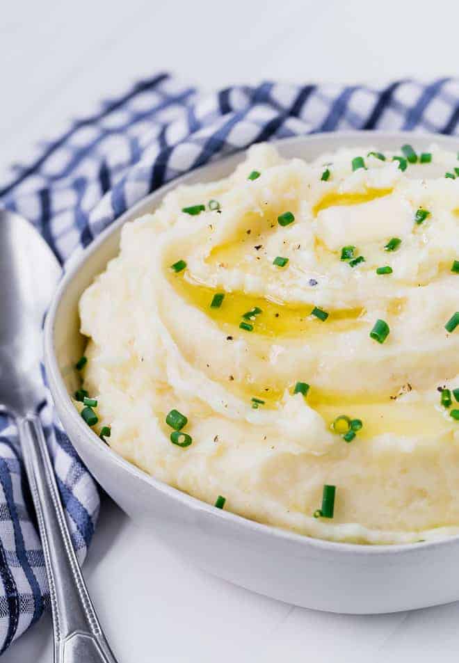 Creamy mashed potatoes in a bowl topped with melting butter and chives. 