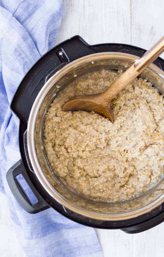 Image of steel cut oatmeal in an instant pot with a wooden spoon.