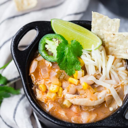 Image of pressure cooker white chili in a black bowl with garnishes.