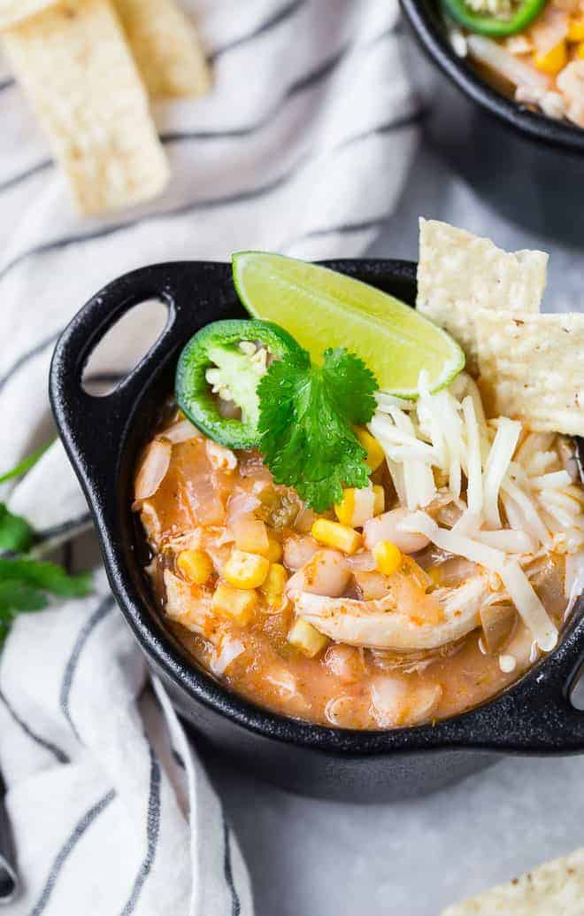 Image of pressure cooker white chili in a black bowl with garnishes.