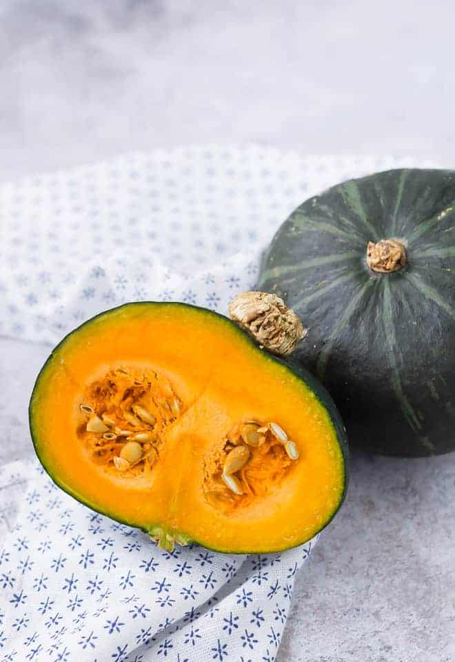 Whole kabocha squash and a half kabocha squash with the seeds still present.